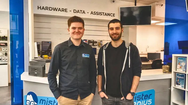 Twee technici aan balie van winkel Mister Genius in Luik