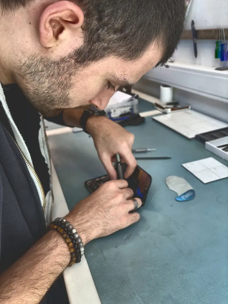 Technicus opent iPhone aan werkbank in winkel Mister Genius Luik