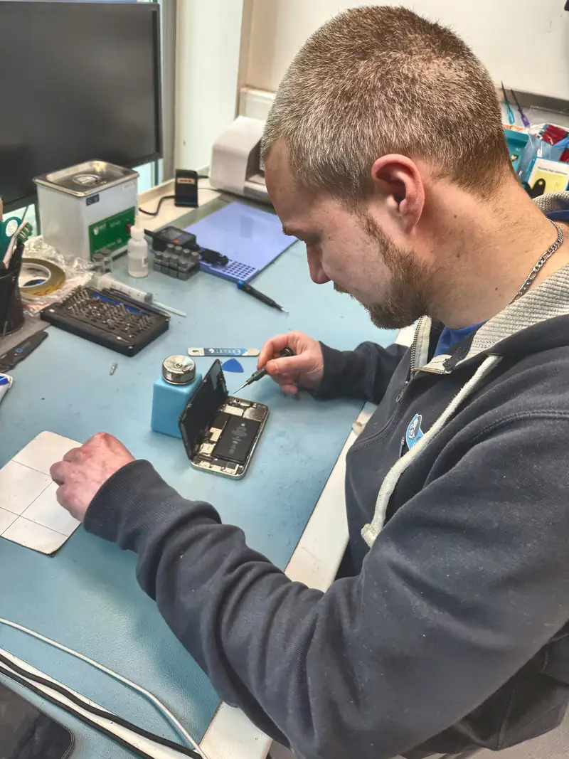 Technician repairing smartphone at Mister Genius workbench, Woluwe-Saint-Lambert